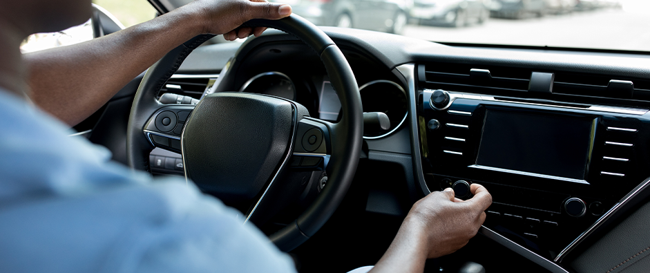 Unrecognizable black man driver turning on radio in auto